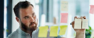 Professional man engaging in strategic planning using a transparent board with color-coded sticky notes.